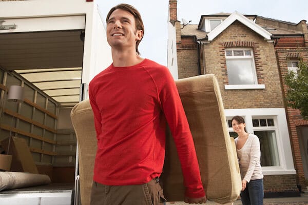 young couple moving a couch out of a townhouse