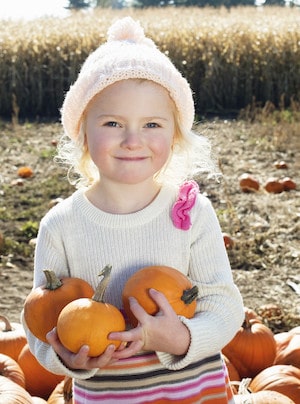 Portrait of a happy girl holding pumpkins in farm